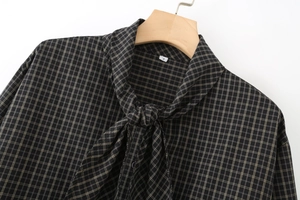 Detail of a brown plaid long sleeve shirt featuring a lace-up neckline on a wooden hanger
