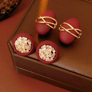 Close-up of vintage gold-plated oval earrings with deep red finish and zircon crystals