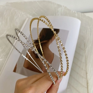 Close-up of gold and silver rhinestone crossover headbands held by hand over a magazine