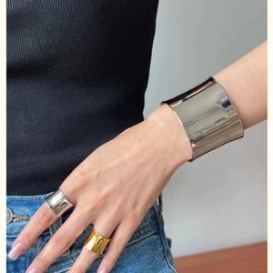 Minimalist wide silver open cuff bracelet and gold ring set on female model's wrist