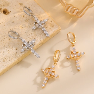Detailed macro shot of gold and silver cross earrings with crystals on stone tray