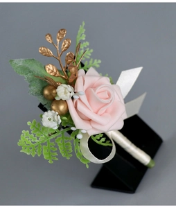 Close-up of handmade pink foam rose boutonniere with gold leaf accents on a display stand