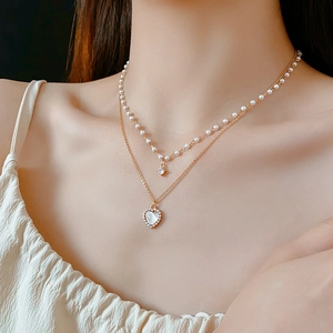 Vue détaillée du collier double épaisseur avec cœur, perles et zircon porté par un mannequin