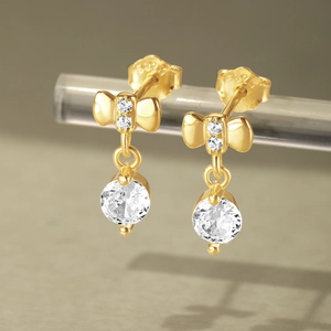 Macro view of gold S925 silver bow earrings with round clear stones and hallmark