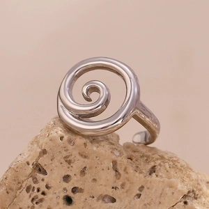 Detailed close-up of a silver spiral open ring placed on a textured natural stone base