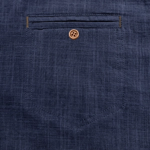 Macro detail of navy cotton linen shirt featuring a textured pocket and wooden button