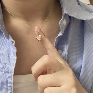 Close-up of gold plated heart pendant necklace with shimmering crystals on model