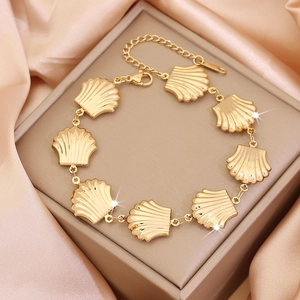 Detail of a gold scallop shell bracelet on jewelry box with champagne satin background