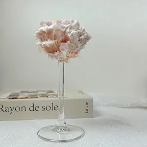 Artistic seashell glass ornament on a white fabric surface with a minimalist grey backdrop