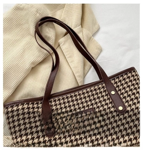 Macro shot of houndstooth tote bag with brown leather handles on textured fabric