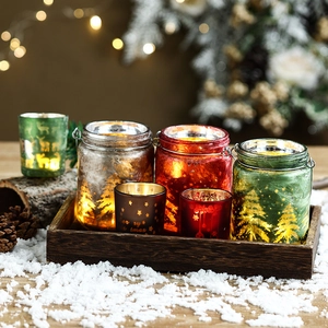 Set of Christmas themed glass candle holders with reindeer and tree patterns in holiday scene