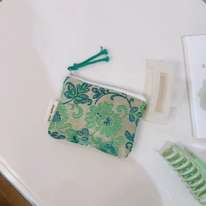 Detailed close-up of a floral jacquard coin purse with green floral patterns and zipper