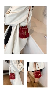 Detail of red quilted mini bucket bag with gold chain strap and heart-shaped pocket
