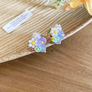 Vista detallada de los pendientes de flores con cuentas de colores sobre fondo de madera.