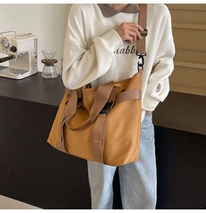 Detail of tan nylon tote bag showing adjustable strap and buckle on casual crossbody