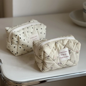Detail of quilted corduroy mini pouches featuring floral and heart patterns with zippers