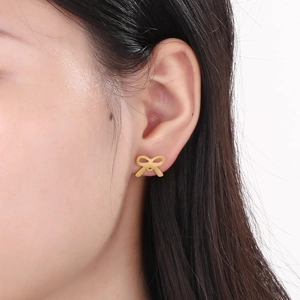 Minimalist gold hollow bow earrings on model showing aesthetic style and daily wear look