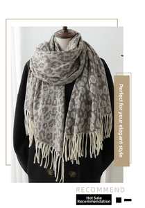 Detail of leopard jacquard scarf with fringe trim worn over a black winter coat
