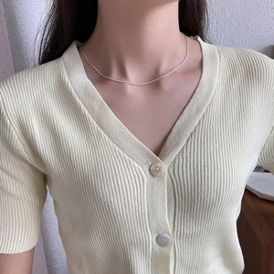 Detailed view of minimalist 925 sterling silver snake chain on a yellow knit sweater