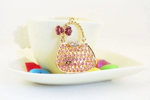 Creative handbag keychain with pink rhinestones hanging on a white teacup rim