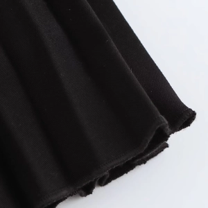 Close-up of pleated hem details on black mini skirt showing fabric texture and craftsmanship