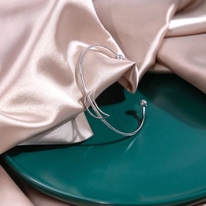Detail of silver open cuff bracelet with hollow crescent moon design on silk fabric