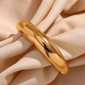 Detailed macro view of gold-plated stainless steel cuff bracelet on champagne silk