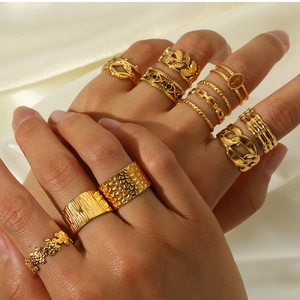 Close-up of stacked gold titanium steel rings with textured designs on silk fabric