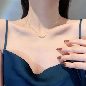 Elegant gold bead necklace with five round charms on a model with a blue silk dress