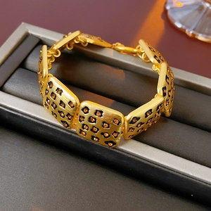 Detailed close-up of a gold leopard print bracelet with orange rhinestones in a display box