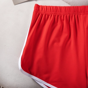 Detail of red athletic shorts featuring white trim and elastic waistband fabric
