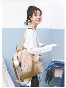 Détail du sac à dos rose à fleurs avec bretelles en cuir marron et pendentif pompon blanc
