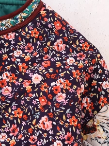Detailed close-up of dark purple quilted jacket featuring floral prints and teal lining
