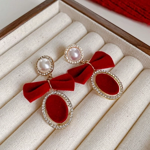 Détail de boucles d'oreilles nœud velours rouge avec perles et strass en coffret