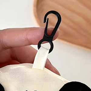 Detail of the black plastic hook and white fabric strap on the portable shopping bag