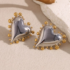 Macro shot of two-tone stainless steel heart earrings with gold bead trim and silver finish