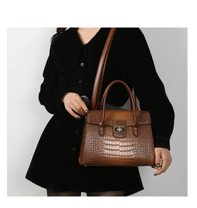 Detail of a brown crocodile pattern shoulder bag with a gold twist lock closure