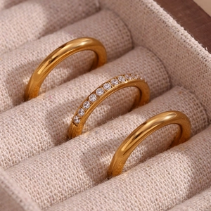 Macro shot of three 18K gold plated rings with zircons set in a beige fabric jewelry box