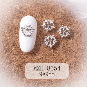 Macro view of 9x9mm silver snowflake nail charms with center crystal for winter DIY art