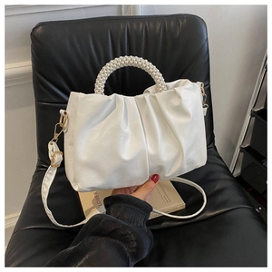 Detail of white pleated handbag featuring pearl bead handle and detachable shoulder strap