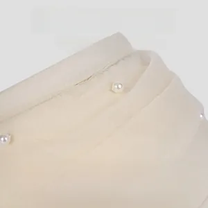 Detailed macro view of ivory mesh sun hat with intricate pleats and pearl embellishments
