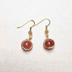 Gros plan de boucles d'oreilles en or 14K avec pierres précieuses marron-rouge serties