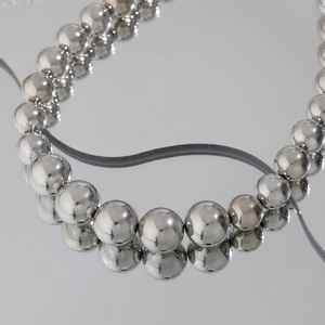 Macro shot of shiny silver beaded necklace reflecting on a premium mirror surface