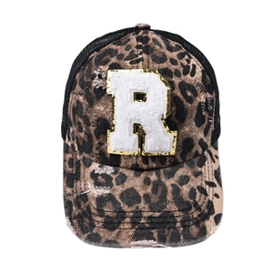Detail of leopard print baseball cap featuring a white fuzzy R patch with gold sequins