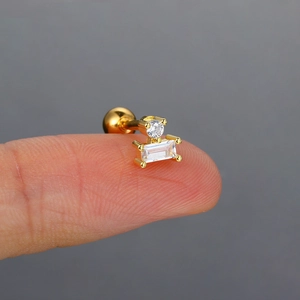 Detalle macro del pendiente de oro y circonita en la punta del dedo para escala real