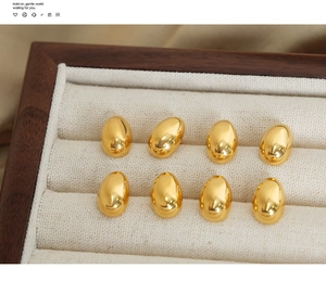 Macro detail of polished gold teardrop charms resting on a velvet jewelry display tray