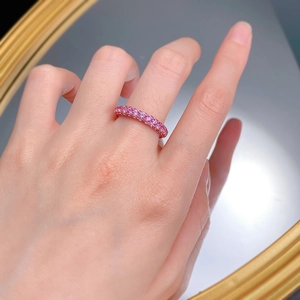 Detailed view of pink eternity ring with sparkling stones on model's finger