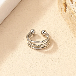 Three-layer silver beaded ear cuff with a polished metallic finish on a neutral surface