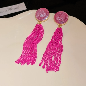 Detailed view of rose red pearlescent earrings with long metallic fringe chains