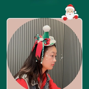 Dettaglio mini cappello di Natale verde per capelli con nastri rossi e pizzo